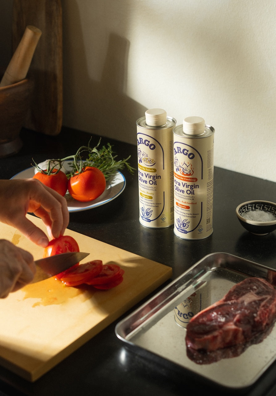 Both Argo tins on a kitchen counter with tomato, bread and garlic